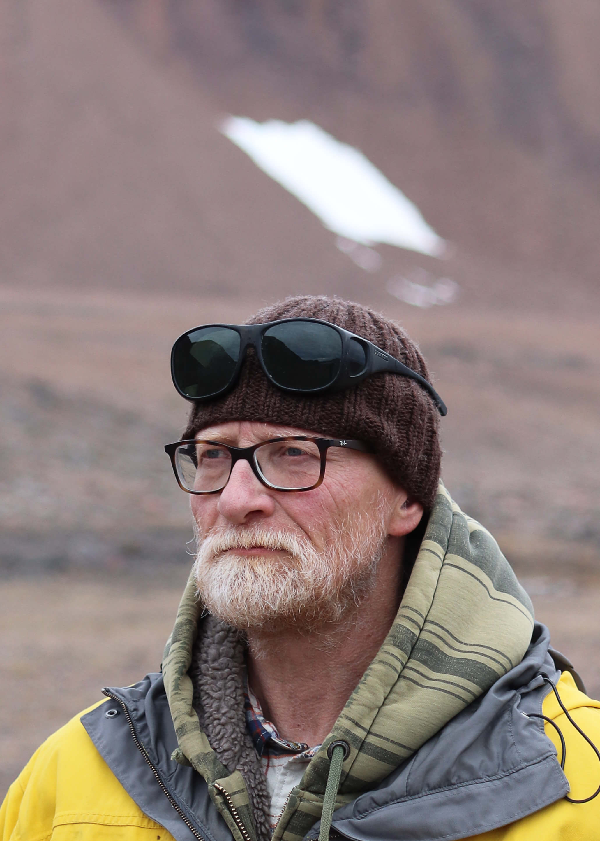 portrait of a man wearing glasses, a yellow jacket and a beanie